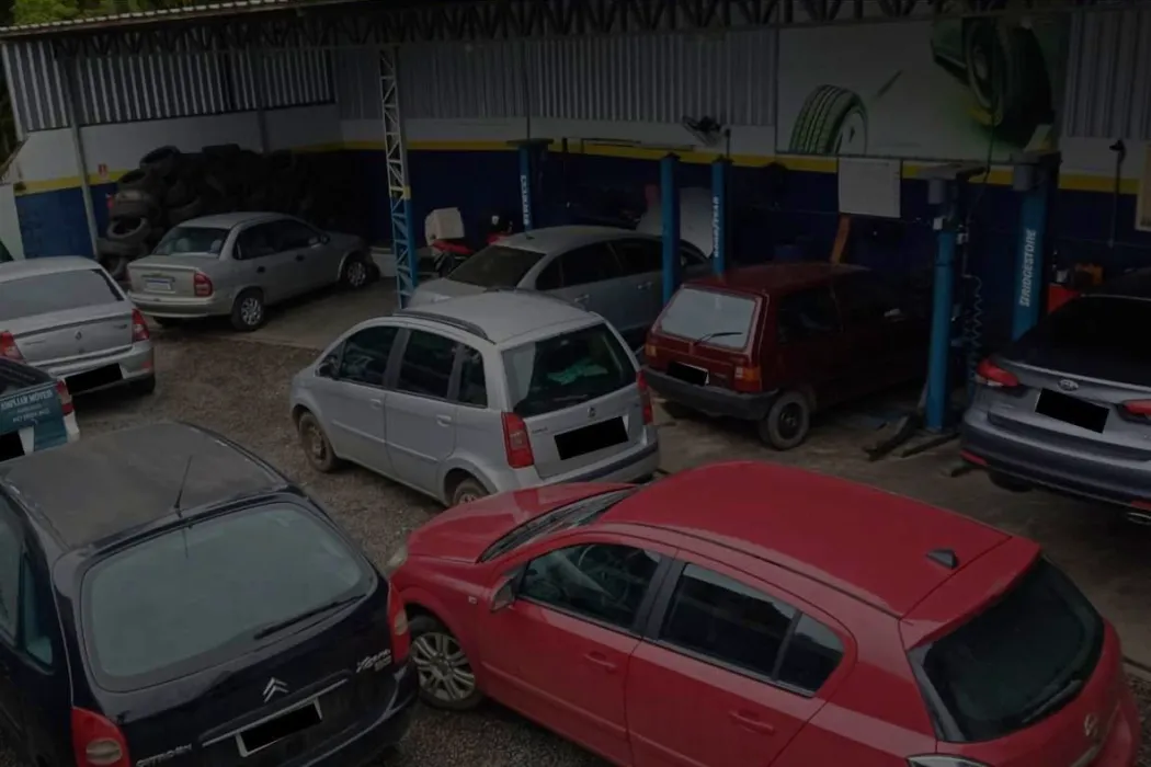 Pátio da oficina com vários carros aguardando atendimento e elevadores ao fundo