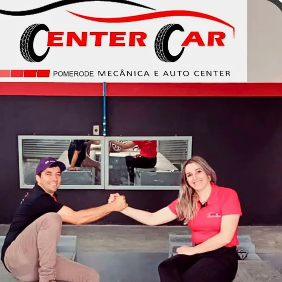 A dupla da Center Car sentada na beira do box da unidade de Pomerode, sob a placa da loja